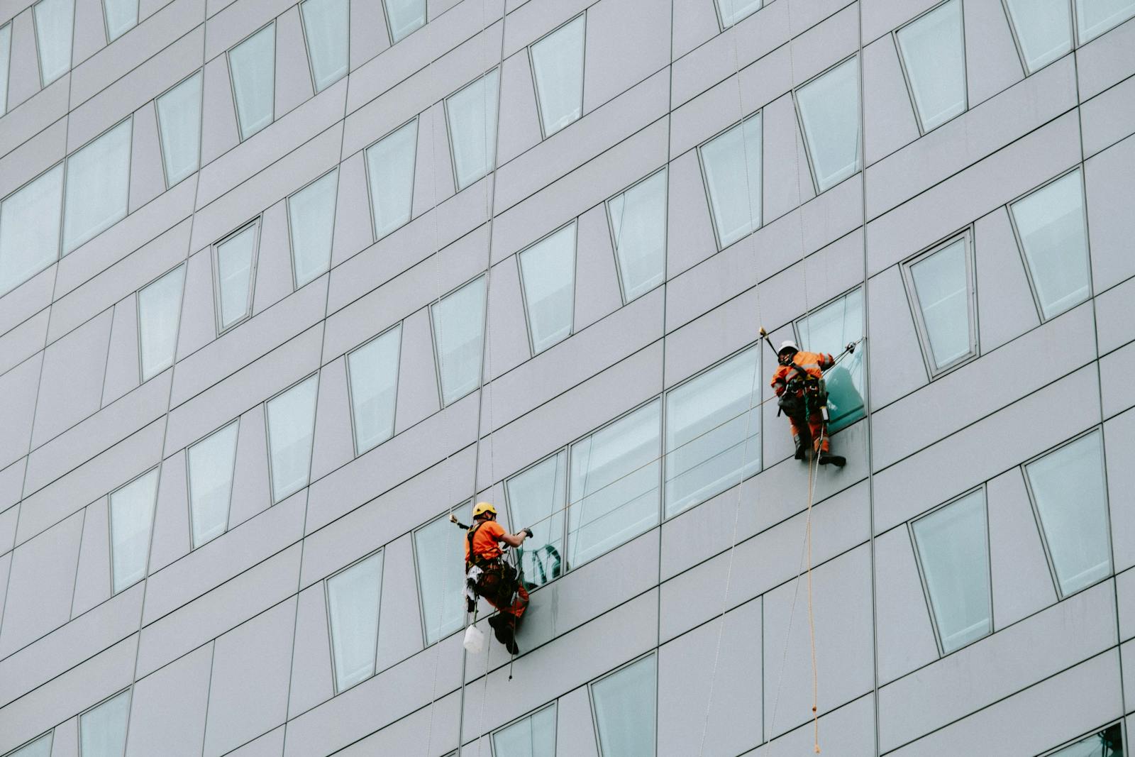 Two Male Rope Access Workers Washing the Windows of a Modern Building